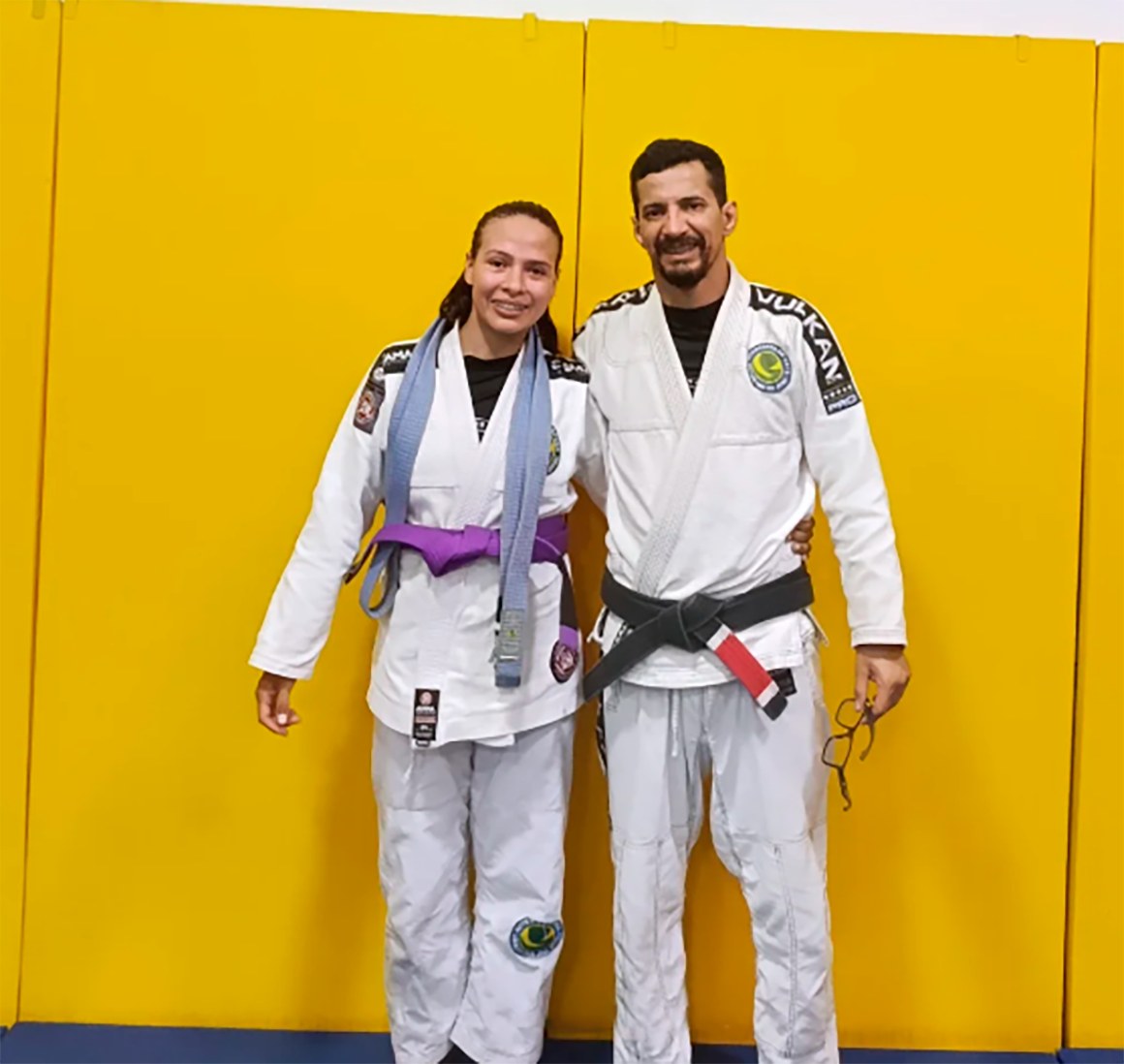 Professor amarrando a faixa em um aluno durante cerimônia de graduação